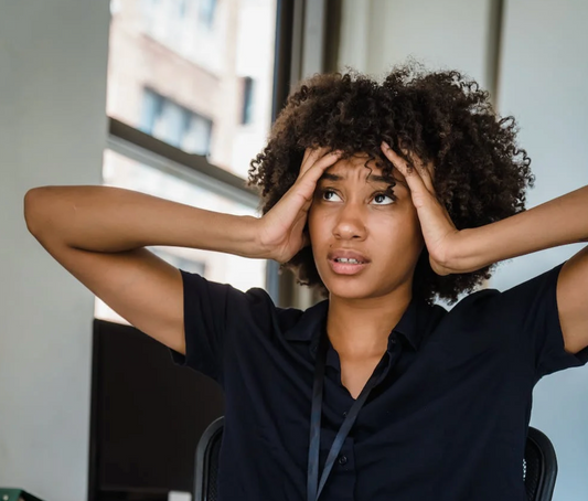 femme aux cheveux crépus qui se tient la tête